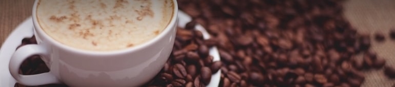 coffee beans next to a cup of coffee